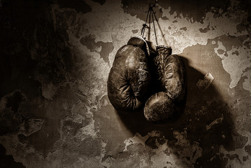 old boxing gloves hang on nail on texture wall