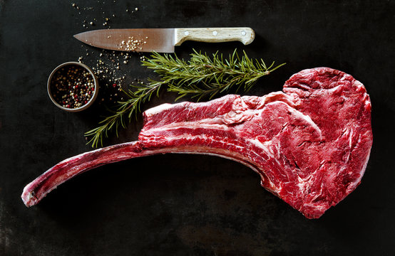 Raw tomahawk beef steak with ingredients