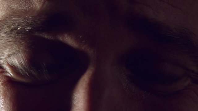 Crying man with tears in eyes, closeup with dramatic light