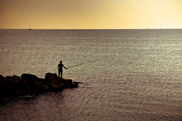 Fototapeta premium Silhouette of a fisherman at sunset in the Mediterranean sea