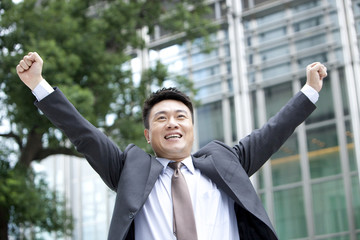 Mature businessman punching the air excitedly outdoors, Hong Kong