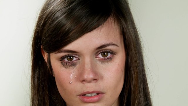 Emotional person. Young crying girl on neutral background