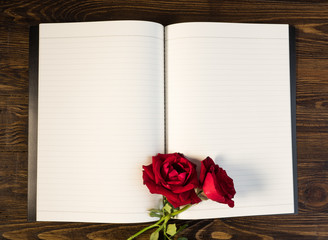 rose and empty notebook page on wood background