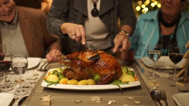 4k footage, closeup senior woman slicing roasted turkey on dining table at christmas eve, captured with atomos shogun
