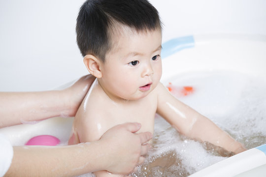 Mother washing baby in bathtub
