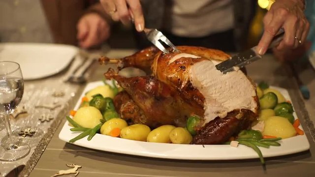 4k footage, detail woman cutting roasted christmas turkey on dining table and serving slices on plate, captured with atomos shogun
