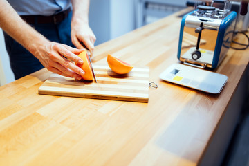 Man slicing orange in kitchen