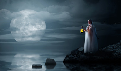 Elven girl with lantern on night sea coast