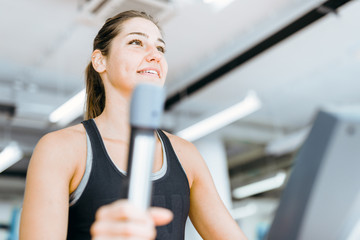 Beautiful young lady using the elliptical trainer