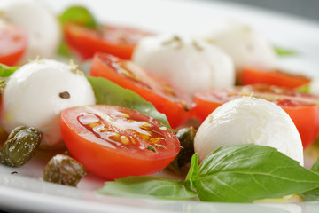 caprese salad with mini mozzarella balls, tomatoes and capers