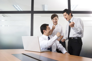 Young businessmen and businesswoman celebrating in office