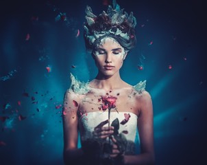 Winter beauty fantasy woman portrait. Beautiful young model girl and blast of frozen rose. - obrazy, fototapety, plakaty