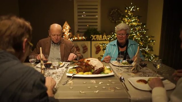 4k footage, dolly move four seniors enjoying roasted turkey on christmas eve in living room, captured with atomos shogun
