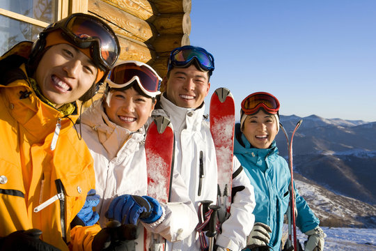 Four young people with their ski equipment