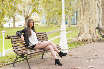 Smiling beautiful woman sitting on wood bench, outdoor.