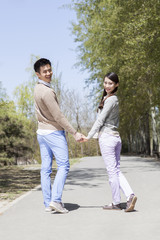 Obraz premium Happy young couple looking over shoulders hand in hand