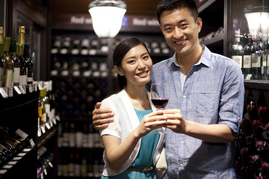 Portrait of couple holding a glass of wine in the wine cellar