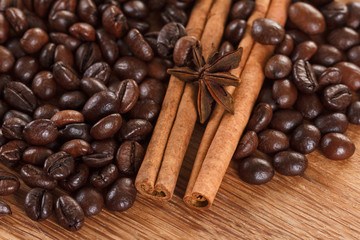 Coffee beans with cinnamon and anise on wooden table