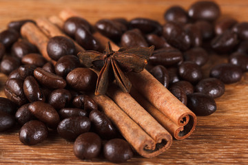 Coffee beans with cinnamon and anise on wooden table