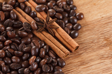 Coffee beans with cinnamon and anise on wooden table