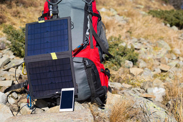 The solar panel attached to the tent. The man sitting next to mobile phone charges from the sun.