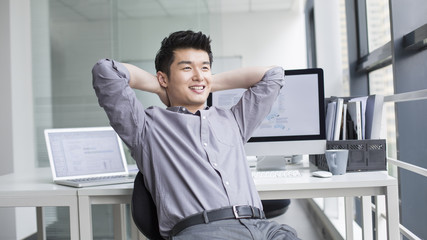 Young businessman looking through window in office