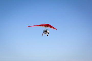Motorized hang glider soaring in the blue sky