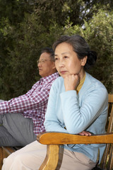 Man And Woman Sitting On Park Bench 