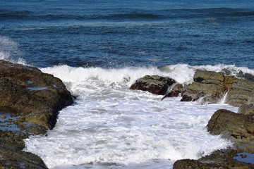 Fototapeta na wymiar 庄内浜の荒波（初夏）／山形県庄内浜の荒波風景を撮影した写真です。庄内浜は非常にきれいな白砂が広がる海岸と、奇岩怪石の磯が続く大変素晴らしい景観のリゾート地です。晴天で強風の海岸で、荒波を撮影した写真です。
