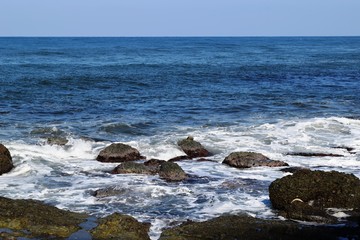 Fototapeta na wymiar 庄内浜の荒波（初夏）／山形県庄内浜の荒波風景を撮影した写真です。庄内浜は非常にきれいな白砂が広がる海岸と、奇岩怪石の磯が続く大変素晴らしい景観のリゾート地です。晴天で強風の海岸で、荒波を撮影した写真です。 