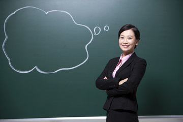 Cheerful female teacher arms crossed in classroom