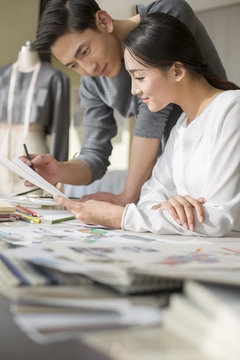 Two fashion designers looking at sketch