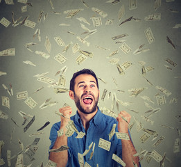 happy man pumping fists celebrates success screaming under money rain