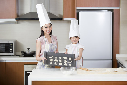 Happy mother and daughter baking cookies