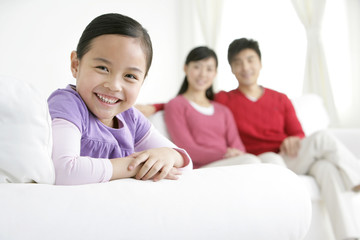 Young Chinese girl in a living room with parents in the background