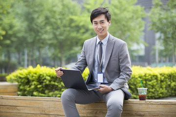 Young businessman working with laptop outdoors