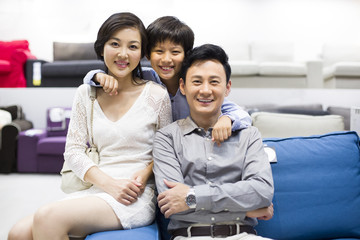 Cheerful family sitting in couch in furniture shop