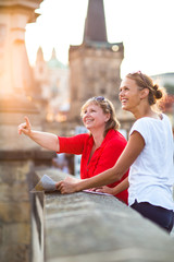 Mother and daughter traveling - two tourists studying a map - obrazy, fototapety, plakaty
