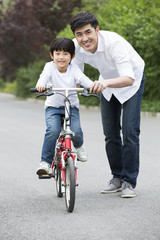 Obraz premium Father teaching son to ride a bicycle