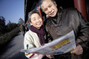 Elderly Couple Holding Newspaper