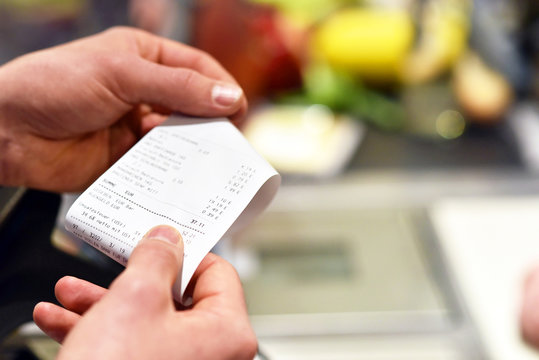 Hände mit Kassenzettel an der Kasse im Supermarkt // hands with receipt at the checkout in the supermarket