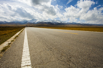 Road going through field into the mountains in Qinghai province, China