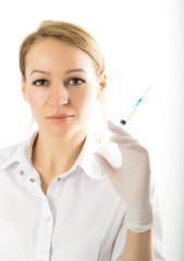 beautiful young female doctor in medical gown and rubber gloves holding a syringe. nurse