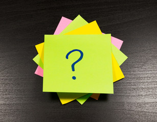 question mark on a sticky note on wooden background