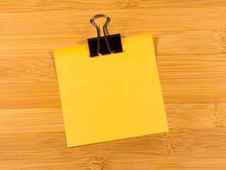 Sticky note on wooden background, empty space for text