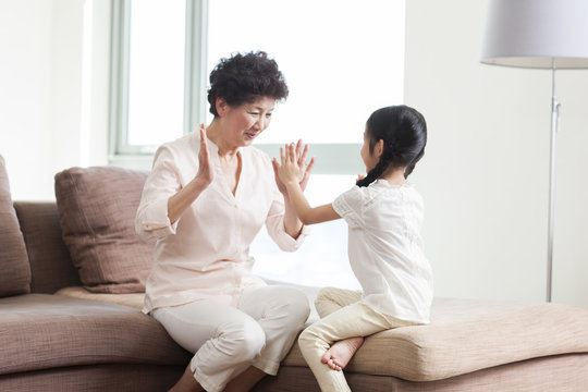 Happy grandmother and granddaughter playing clapping game - Powered by Adobe