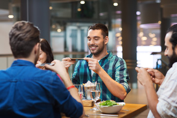 happy friends taking picture of food at restaurant
