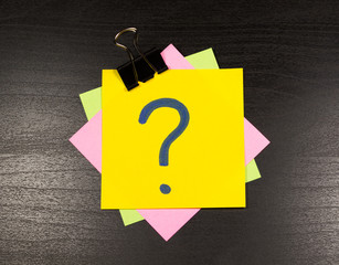question mark on a sticky note on wooden background