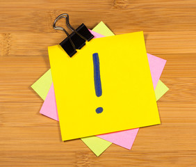 exclamation mark on a sticky note on wooden background