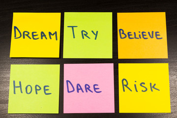 dream try believe hope dare risk sticky note on wooden background